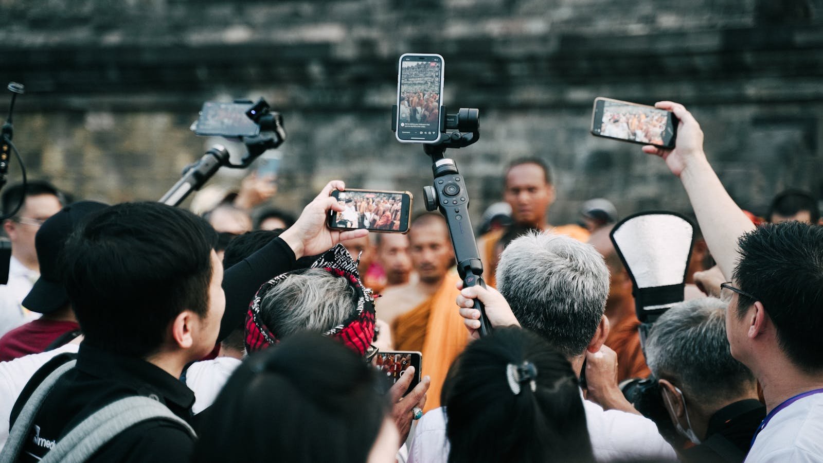 A crowd uses smartphones to capture a Buddhist ceremony at a historic site.